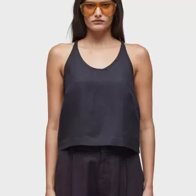 Mulher vestindo regata preta e calças largas pretas com óculos de sol amarelos