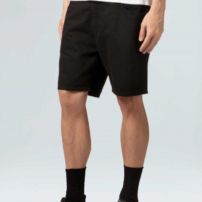 Calções pretos masculinos usados com camiseta branca e calçado preto.