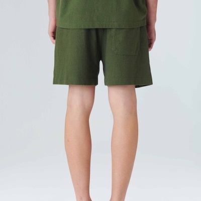 Pessoa vista de costas com calções e camisola verde e calçado bege.