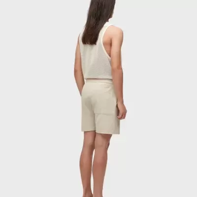 Pessoa com roupa bege texturizada e sandálias castanhas vista de trás