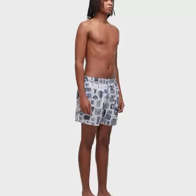 Homem jovem com calções de banho brancos estampados e chinelos de dedo