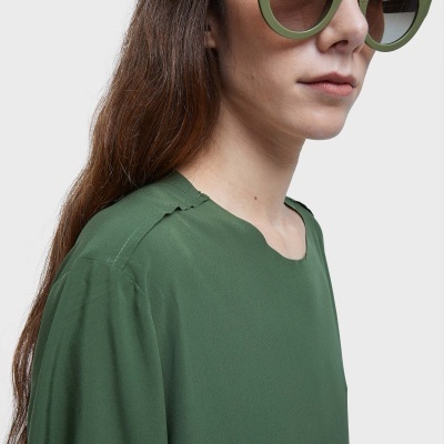 Óculos de sol verdes foscos com lentes escuras em mulher com camisa verde