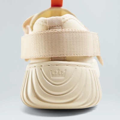 Ténis creme visto de trás com tira ajustável e sola com relevo de coroa