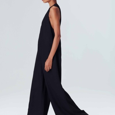 Mulher vestindo macacão preto largo sem mangas com chapéu de palha e sandálias