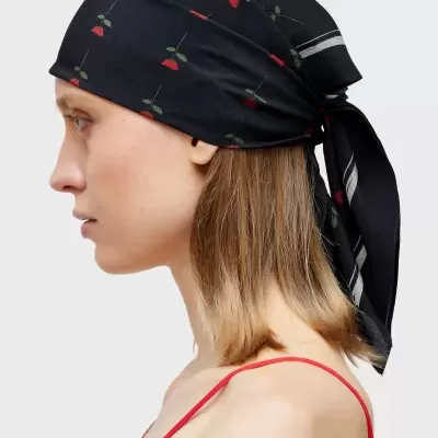 Mulher de perfil com lenço preto estampado e top vermelho