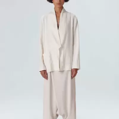 Modelo feminina veste casaco branco de manga comprida e saia comprida bege claro