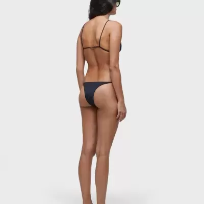 Mulher de pé de costas a usar biquíni preto simples e óculos escuros