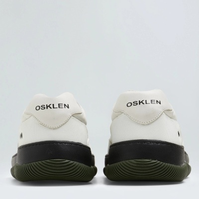 Ténis Osklen vistos da parte traseira em branco com sola verde e detalhes pretos