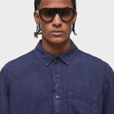 Óculos de sol com armação preta e lentes redondas castanhas, camisa azul escura texturada com bolso