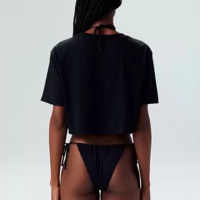 Mulher de costas com t-shirt preta de manga curta e biquíni preto