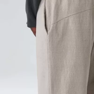 Calças bege claro com elástico e bolsos, parte inferior de camisola preta visível