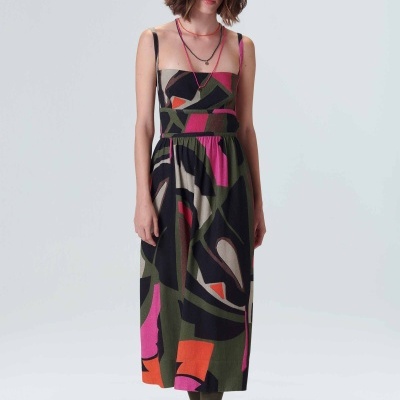 Vestido midi colorido de padrão abstrato em mulher com roupas neutras num fundo branco