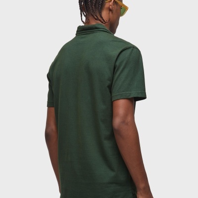 Homem de costas com polo verde escuro e calças claras