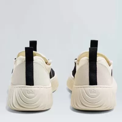 Sapatilhas brancas e pretas vistas de trás com solado almofadado e etiqueta preta