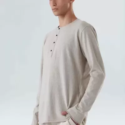 Modelo masculino vestindo camisola bege clara de malha com botões na gola