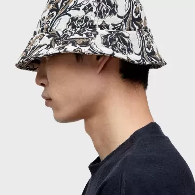 Chapéu bucket floral em preto, branco e castanho usado por pessoa de perfil