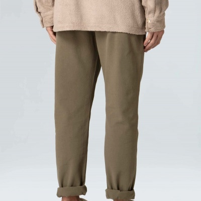 Pessoa vista de costas com calças verde-oliva, casaco bege e sapatilhas bege