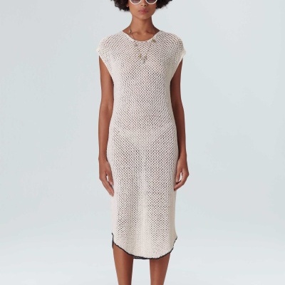 Modelo com vestido de malha crochet bege claro e óculos de sol brancos