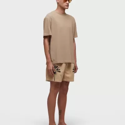 Homem com t-shirt bege e calções com estampa preta