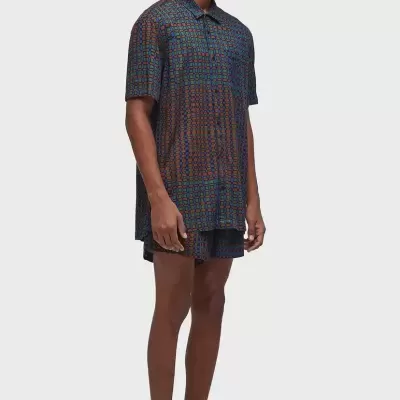 Homem com conjunto de camisa e calções de padrão geométrico colorido e óculos escuros amarelos