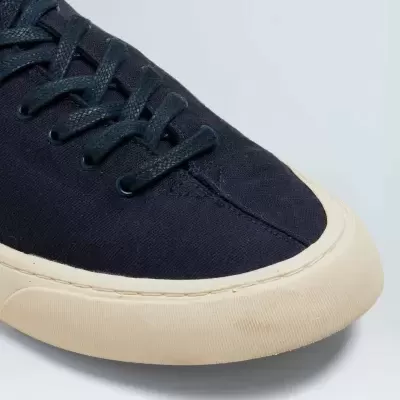 Ténis azul escuro com sola creme em fundo cinzento