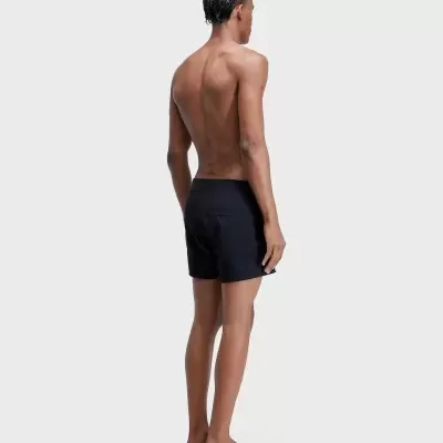 Homem de costas com calções pretos e cabelo com tranças