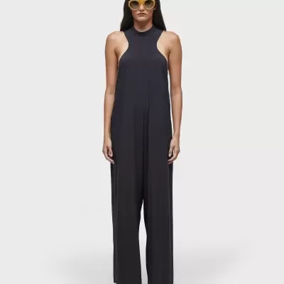 Mulher vestindo macacão preto de tecido fluído e óculos de sol amarelos