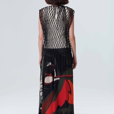 Mulher de costas a usar saia longa com padrão gráfico colorido e blusa de malha preta aberta