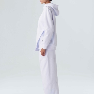 Fato de treino branco com sweat de capuz e calças largas, ténis brancos com azul, vista lateral