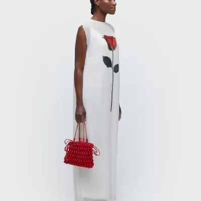 Vestido longo branco com estampa de rosa e mala vermelha trançada