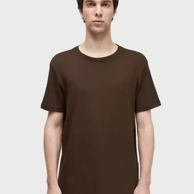 Homem com camiseta castanha de manga curta em fundo branco.