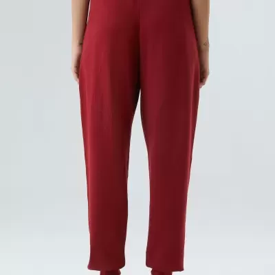 Calças vermelhas de tecido macio com cós largo canelado vistas por trás.