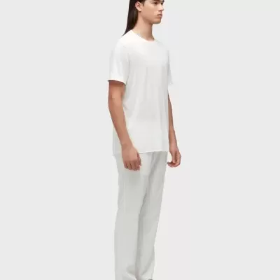 Modelo masculino com t-shirt branca, calças brancas e chinelos brancos