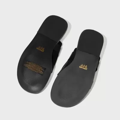 Chinelos planos pretos vistos pela sola com fundo cinza claro