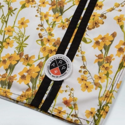 Peça de roupa com padrão floral, riscas pretas e emblema OSKLEN SURF