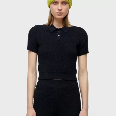 Mulher com conjunto preto de malha e gorro verde limão