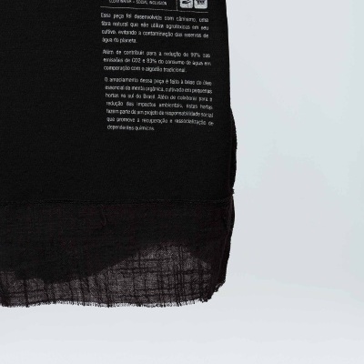 Pano preto com etiqueta da marca OSKLEN e texto em português sobre sustentabilidade em fundo branco.