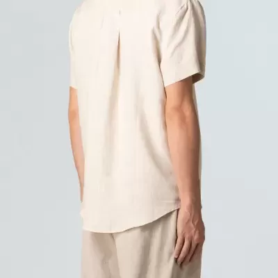 Camisa masculina bege clara de manga curta vista de costas com calças bege claras.