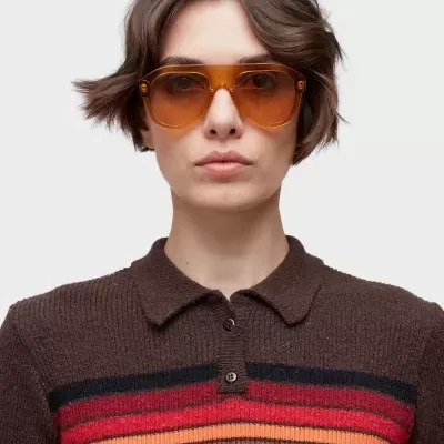 Óculos de sol âmbar aviador em pessoa com camisola castanha de riscas coloridas