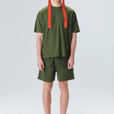 Homem com roupa casual verde e chapéu cinzento com tiras laranja numa pose frontal