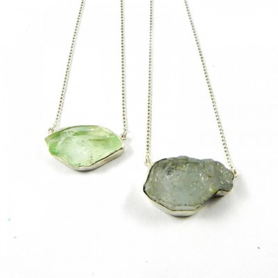 Colares com pedras brutas em metal prateado sobre fundo branco