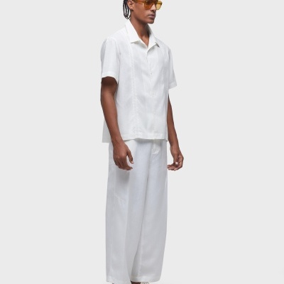 Homem com roupa branca e óculos de sol amarelos em fundo cinza