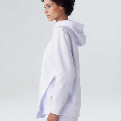 Pessoa de perfil com sweat branco de capuz numa parede branca