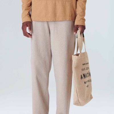 Calças creme, t-shirt castanha clara, sapatos bege e bolsa de tecido bege com texto preto