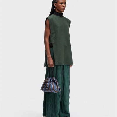 Pessoa com blusão verde escuro e bolsa azul às riscas
