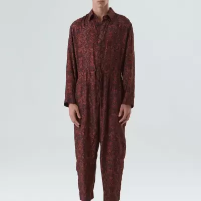 Macacão comprido vermelho e preto com padrão floral usado por um modelo em fundo branco