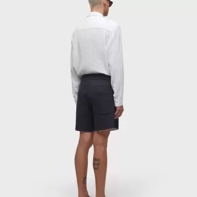 Homem de costas com camisa branca e calções pretos