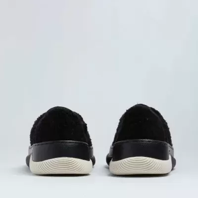 Par de sapatos pretos com pele felpuda e sola branca vistos de trás