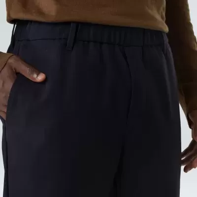 Calças azul escuro com cintura elástica usadas por pessoa com camisola castanha