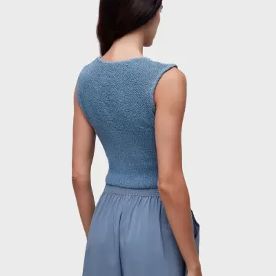 Mulher de costas com top de malha azul e calções azuis